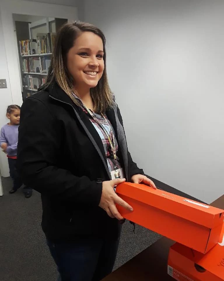 A volunteer carrying wrapped Christmas gift boxes at the C.A.N. extravaganza