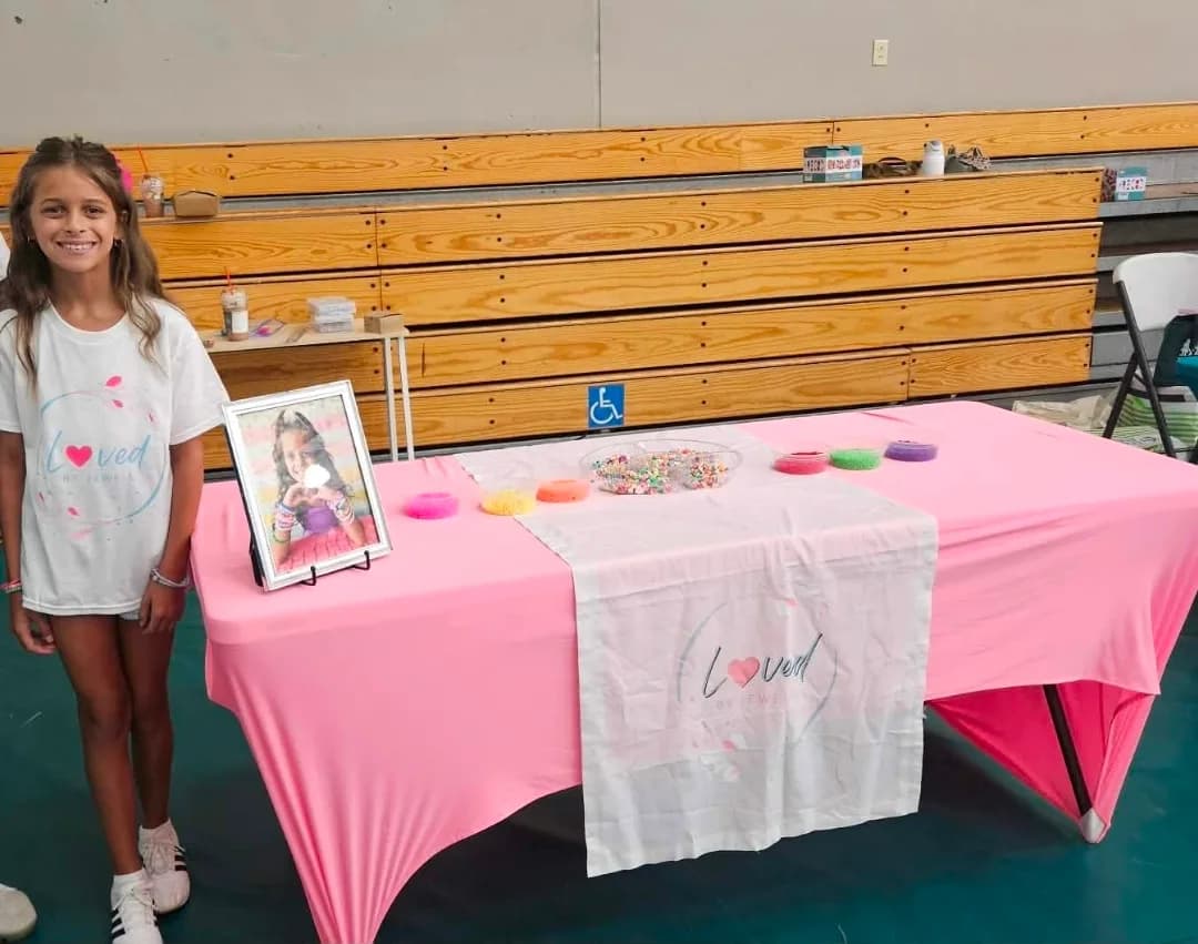 The young founder of Loved by Jewell beside her table of beads and finished bracelets